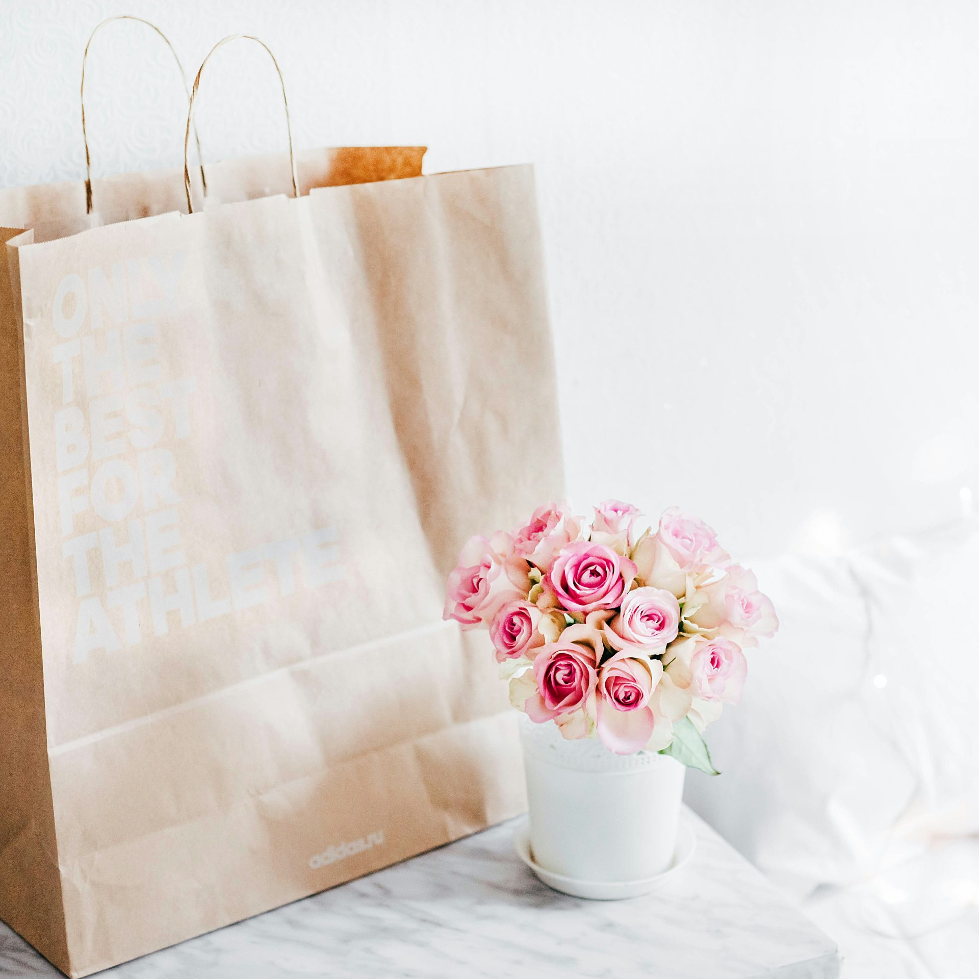 bouquet de roses roses à côté d'un sac en papier marron