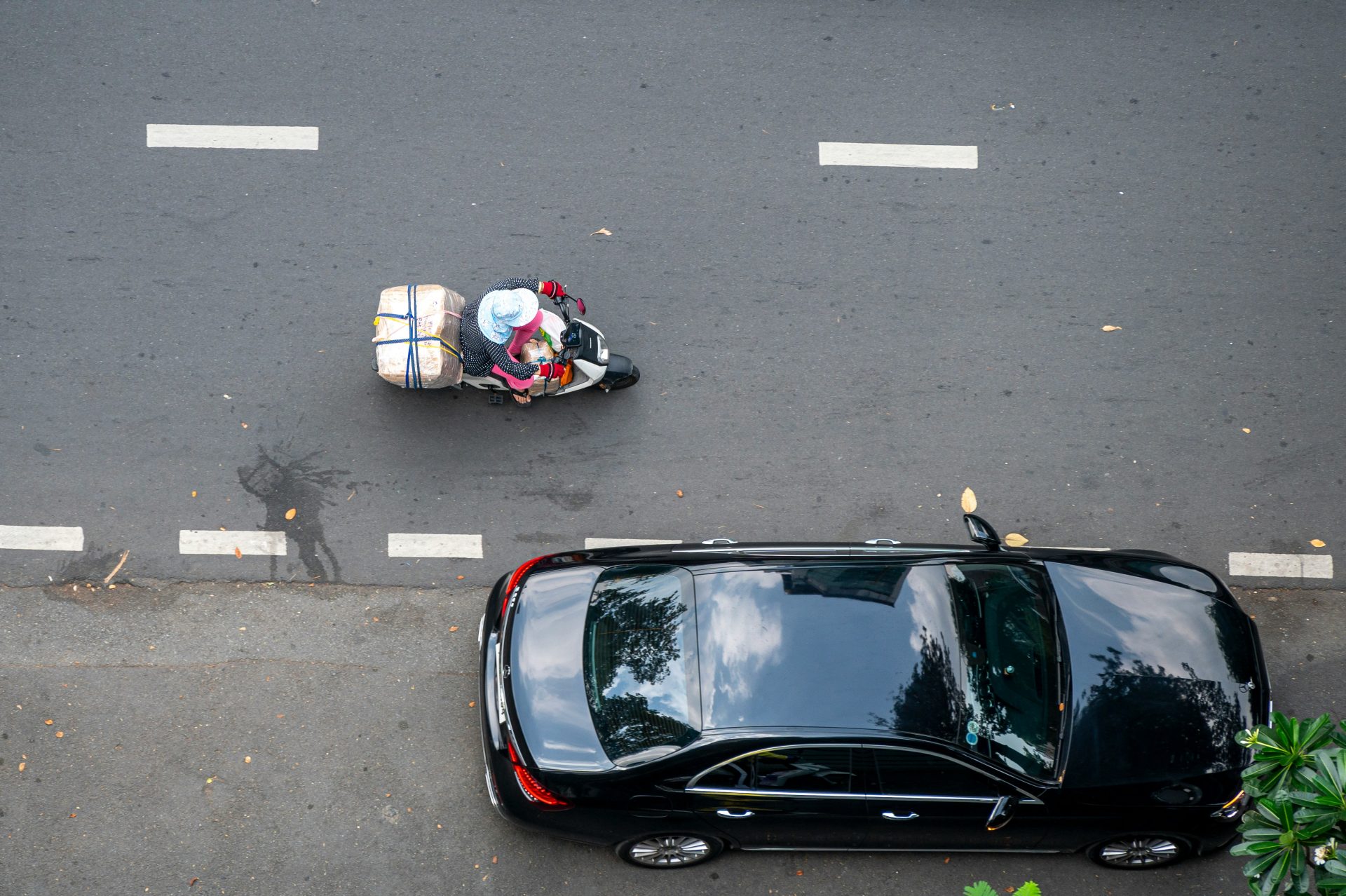 Une voiture noire circulant dans une rue à côté d'une moto